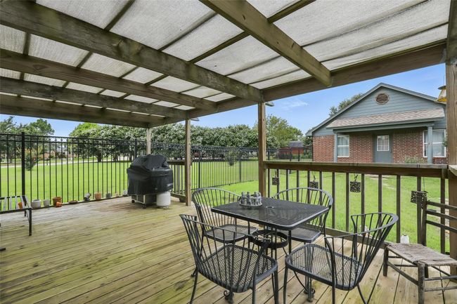 Wooden terrace featuring a grill, outdoor dining space, and a fenced backyard | Image 30