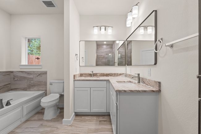 Full bath featuring a bath, toilet, double vanity, marble finish floors, and tiled shower | Image 23