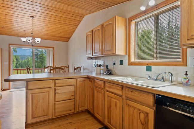 Kitchen featuring black dishwasher, a peninsula, lofted ceiling, a chandelier, and light countertops | Image 29