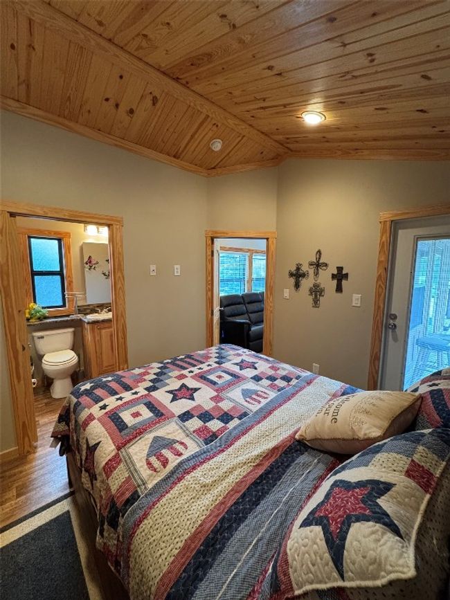 Bedroom with multiple windows, wood finished floors, vaulted ceiling, wood ceiling, and ensuite bathroom | Image 35