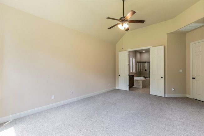 Primary bedroom featuring NEW light carpet, vaulted ceiling, visible vents, baseboards, and connected bathroom | Image 18