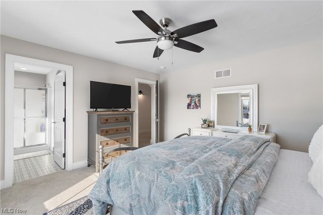 Carpeted bedroom featuring ensuite bathroom and ceiling fan | Image 23