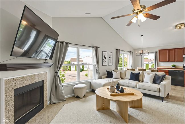 living area with high vaulted ceiling, light colored carpet, a chandelier, a tiled fireplace, and ceiling fan | Image 8