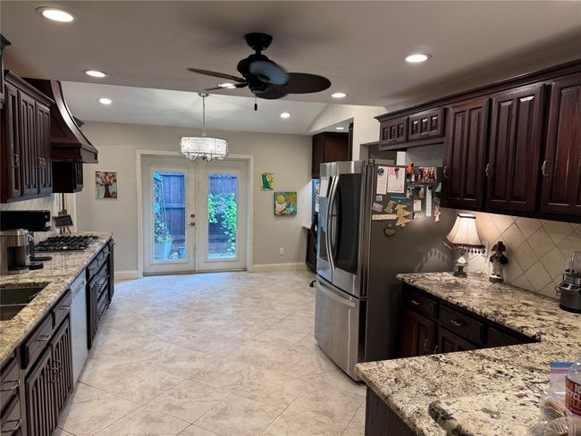 Kitchen with a ceiling fan, tasteful backsplash, stainless steel appliances, dark brown cabinets, and light stone countertops | Image 8