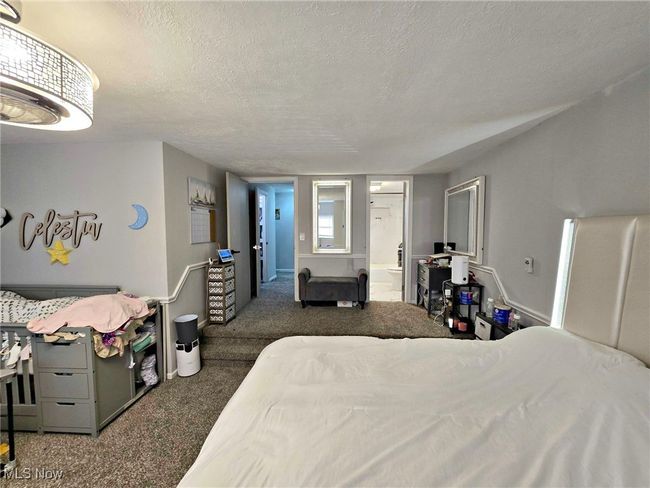 Carpeted bedroom with ensuite bathroom and a textured ceiling | Image 31
