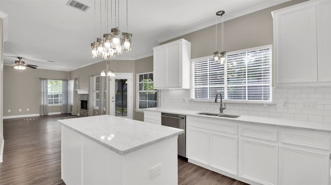 Kitchen with a sink, stainless steel dishwasher, backsplash, a center island, and dark wood finished floors | Image 7