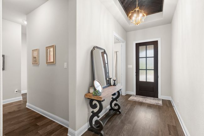 Foyer entrance with dark wood finished floors, a chandelier, and a raised ceiling | Image 26