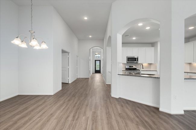 Kitchen featuring stainless steel appliances, wood finished floors, white cabinets, arched walkways, and recessed lighting | Image 14