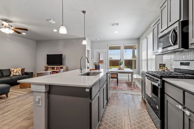 Kitchen featuring appliances with stainless steel finishes, open floor plan, wood finished floors, light countertops, and recessed lighting | Image 6