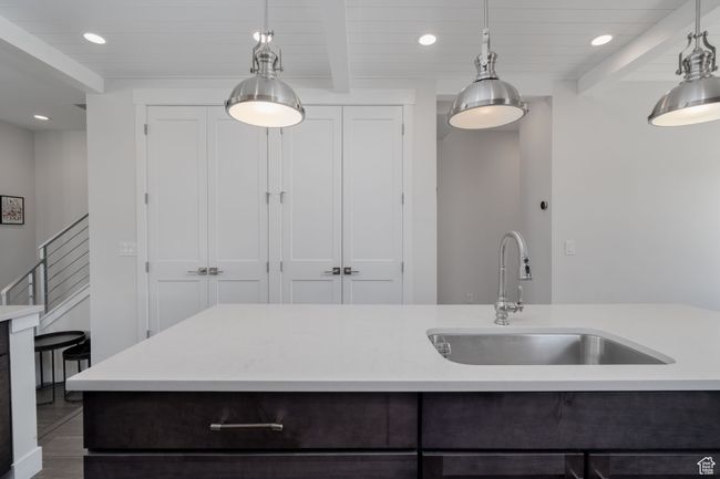 Kitchen with a sink, light countertops, recessed lighting, pendant lighting, and wooden ceiling with exposed beams | Image 14