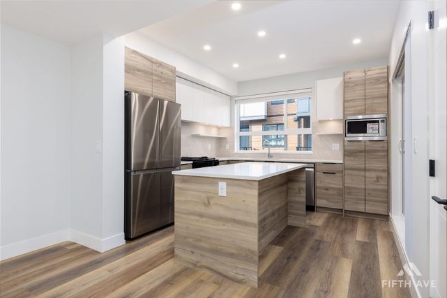 Kitchen featuring appliances with stainless steel finishes, modern cabinets, wood finished floors, recessed lighting, and decorative backsplash | Image 8