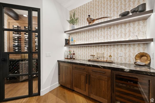 Indoor wet bar featuring beverage cooler, decorative backsplash, and light wood-type flooring | Image 53