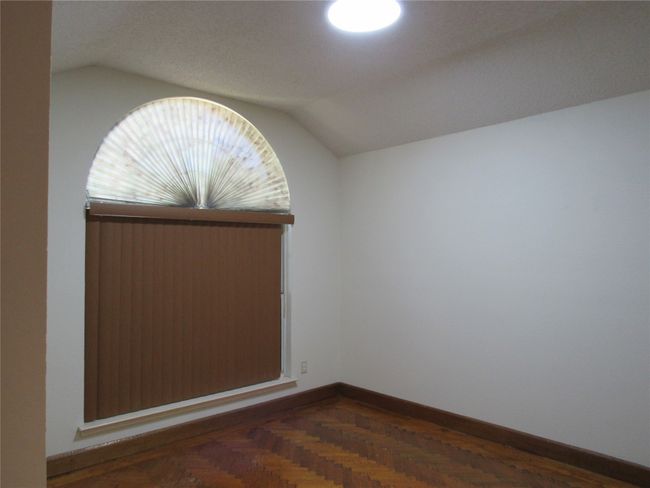 Empty room with vaulted ceiling and baseboards | Image 4