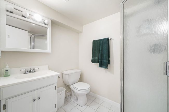 Bathroom with toilet, a stall shower, baseboards, tile patterned flooring, and vanity | Image 27