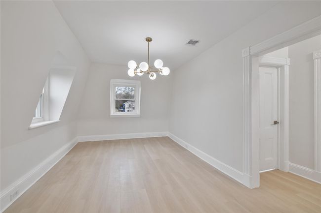 Empty room with light wood finished floors, visible vents, baseboards, and an inviting chandelier | Image 9
