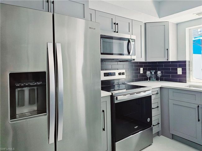 Kitchen featuring gray cabinets, tasteful backsplash, stainless steel appliances, and light countertops | Image 16