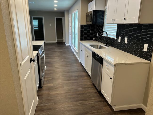 Kitchen featuring a sink, appliances with stainless steel finishes, dark wood-style flooring, tasteful backsplash, and baseboards | Image 9