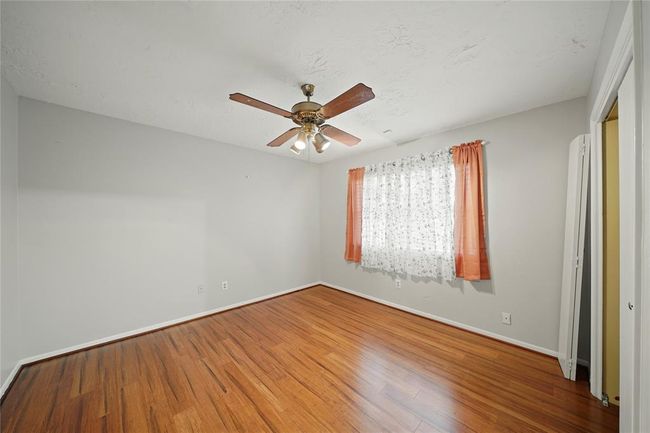 Another bedroom located on the opposite side of the house from primary bedroom, features wood vinyl plank flooring, a ceiling fan, and a window. | Image 20