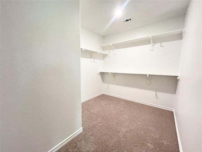 Expansive walk-in closet featuring plush carpeting and ample shelving for organized storage. | Image 18