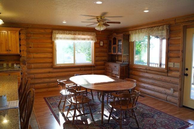 Dining area featuring a ceiling fan, plenty of natural light, wood finished floors, log walls, and recessed lighting | Image 11