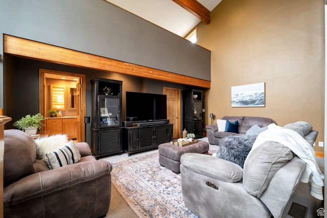 Carpeted living area featuring a high ceiling and beam ceiling | Image 18