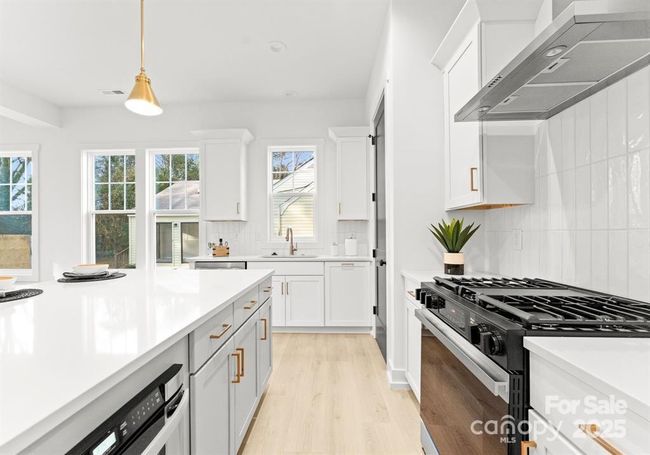 Gourmet kitchen with gas stove with a convection oven and stainless hood that vents to outside. | Image 10