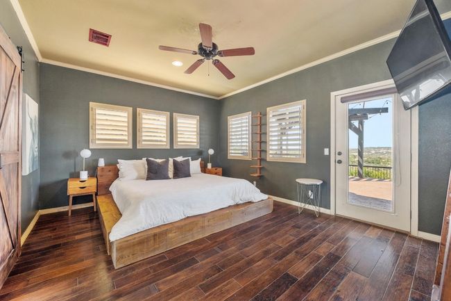 Bedroom with wood finished floors, baseboards, access to exterior, and visible vents | Image 16