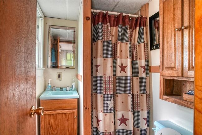 Bathroom with toilet, a shower with shower curtain, and vanity | Image 14
