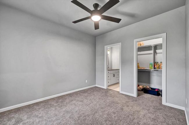 Unfurnished bedroom featuring light carpet, baseboards, a spacious closet, a closet, and ensuite bath | Image 45