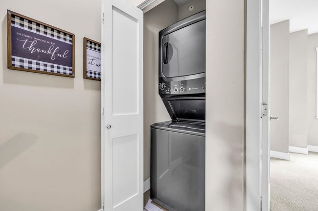 Laundry area featuring estacked washer and dryer, baseboards, and carpet flooring | Image 23