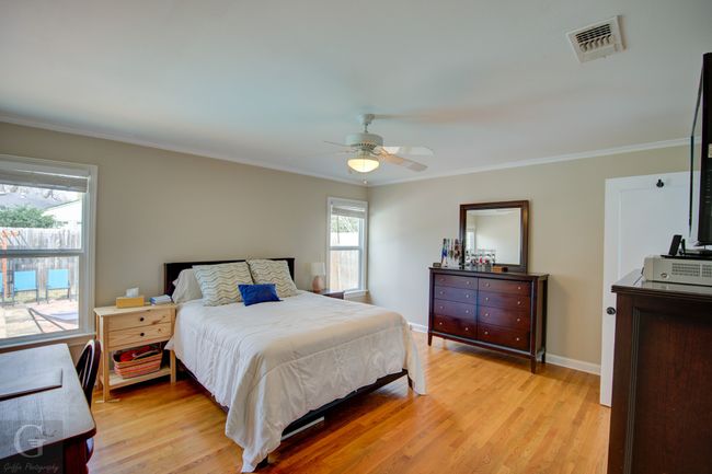 Bedroom featuring baseboards, light wood finished floors, visible vents, and crown molding | Image 17