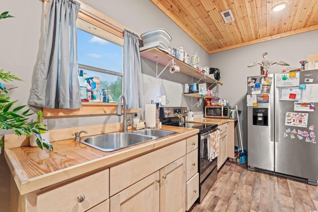 Kitchen with appliances with stainless steel finishes, light brown cabinets, light wood-type flooring, light countertops, and wooden ceiling | Image 32
