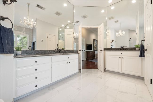 Elegant primary bathroom with dual vanities, recessed lighting and expansive mirrors that enhance the space. | Image 27