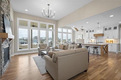 Living room featuring a chandelier, hardwood / wood-style flooring, a fireplace, and plenty of natural light | Image 3