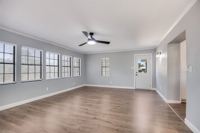 Empty room featuring ornamental molding, ceiling fan, and dark wood-style floors | Image 11