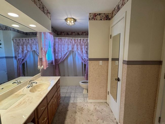 Full bathroom featuring shower / tub combo, tile patterned floors, vanity, and toilet | Image 20