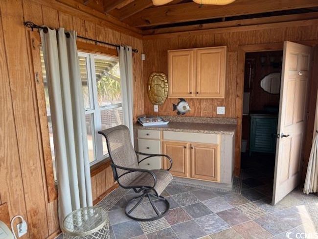 Kitchen with wood walls, light countertops, and stone finish floors | Image 12