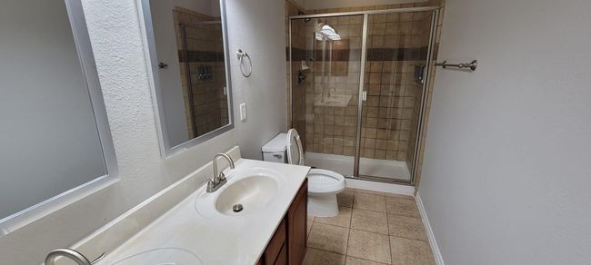 Full bathroom with a shower stall, double vanity, light tile patterned flooring, and a textured wall | Image 15