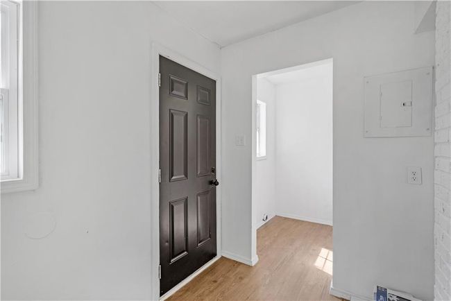 Hall with electric panel, baseboards, and light wood-type flooring | Image 10