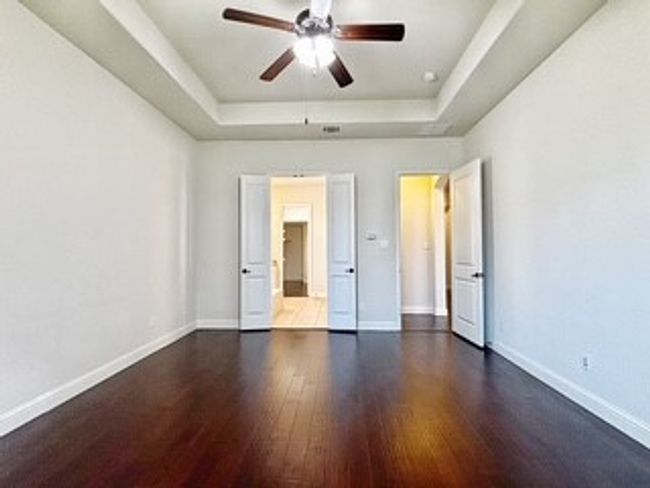 Unfurnished bedroom with a raised ceiling and wood finished floors | Image 13