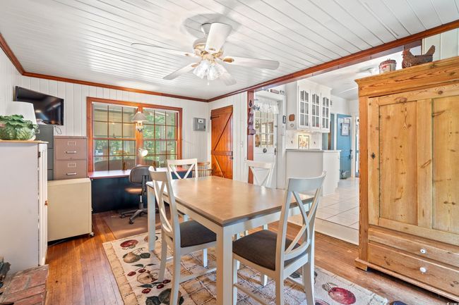 Dining room with crown molding, a ceiling fan, hardwood / wood-style floors, and wood walls | Image 8