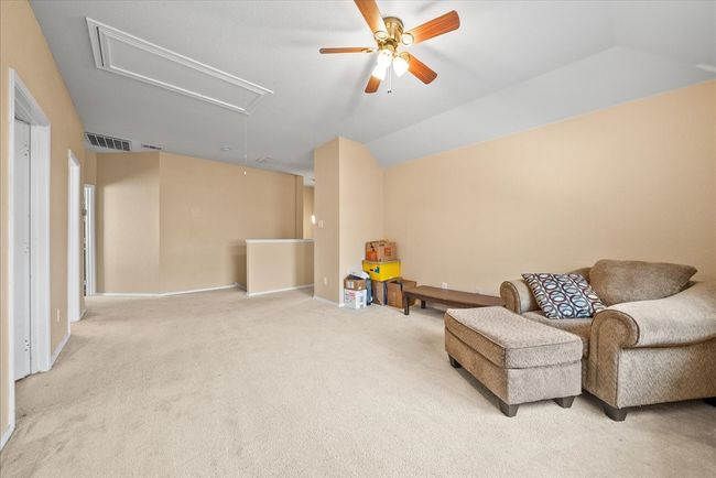 Sitting room featuring attic access, a ceiling fan, carpet floors, lofted ceiling, and baseboards | Image 31