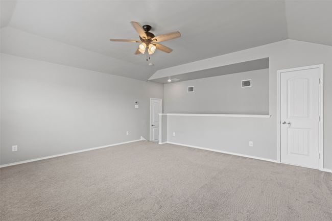 Carpeted spare room featuring lofted ceiling and a ceiling fan located upstairs. | Image 18
