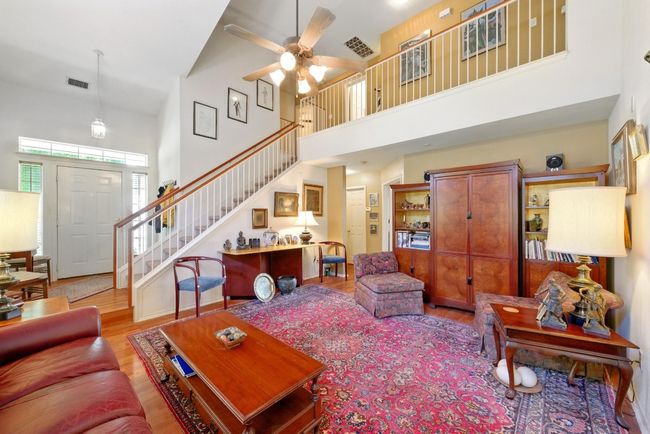 Living area with a towering ceiling, ceiling fan and stairs | Image 7