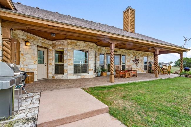Rear view of property featuring stone siding, a patio, a lawn, and a chimney | Image 28