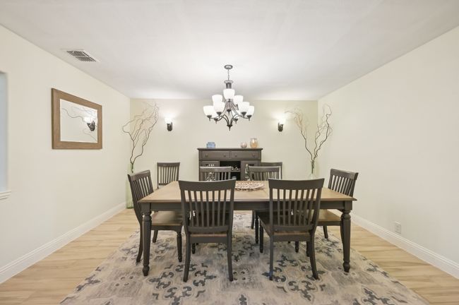 Dining space with baseboards, light wood finished floors, a notable chandelier, and visible vents | Image 9