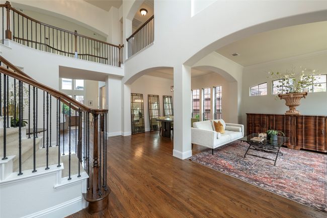 Foyer entrance with wood finished floors, stairs, ornamental molding, a towering ceiling, and arched walkways | Image 5
