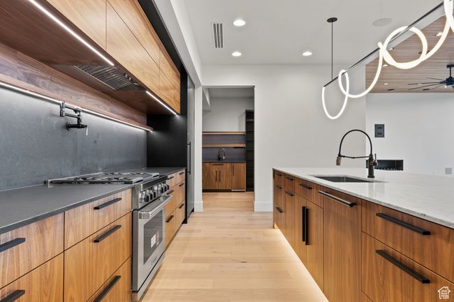 Kitchen featuring high end stainless steel range, modern cabinets, visible vents, and a sink | Image 31