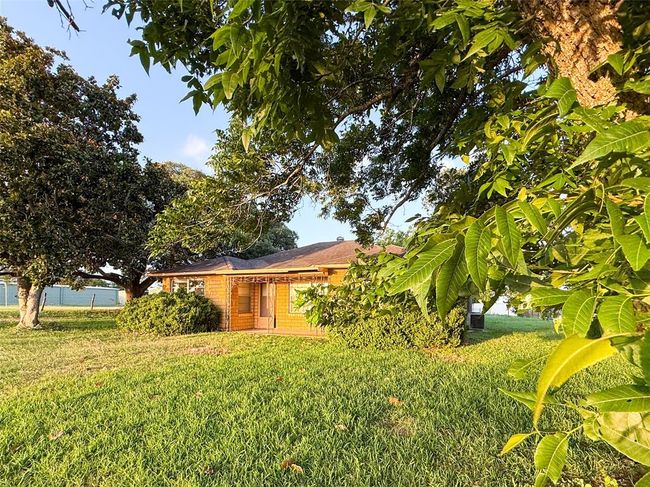 Charming single-story home with a cozy brick exterior, a small covered porch, and manicured bushes. Surrounded by lush greenery, it offers a serene and inviting atmosphere. | Image 17