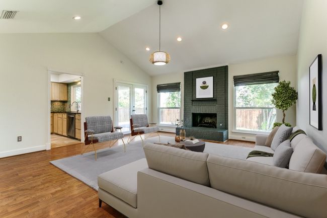 Living area featuring plenty of natural light, a brick fireplace, high vaulted ceiling, light wood finished floors, and recessed lighting | Image 4